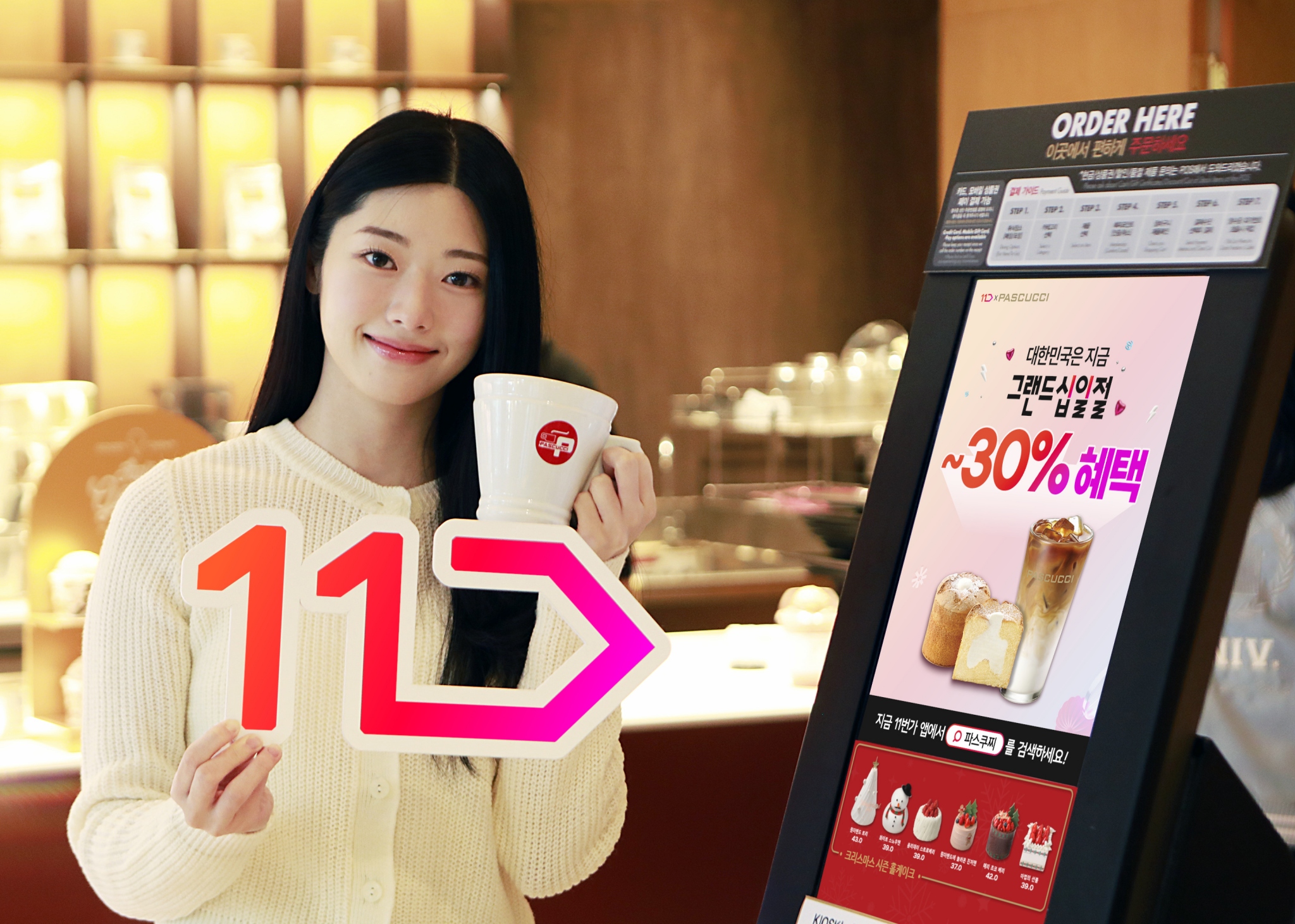 모델이 파스쿠찌 매장에서 11번가 로고와 파스쿠찌 컵을 들고 그랜드십일절을 홍보하고 있다